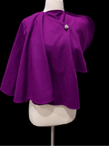 A vibrant purple cape-style top with draped sleeves and a single decorative button at the neckline.